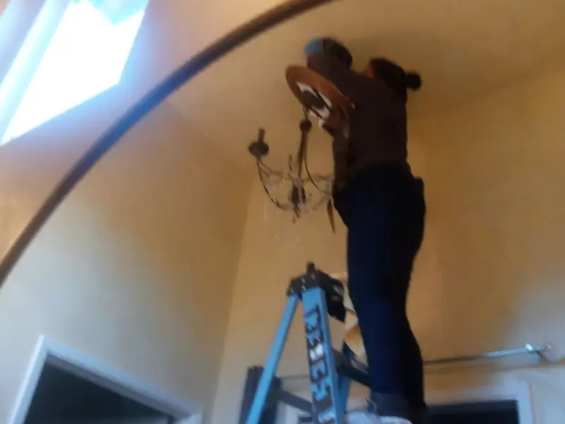 Electrician installing a chandelier in a Brunswick residence